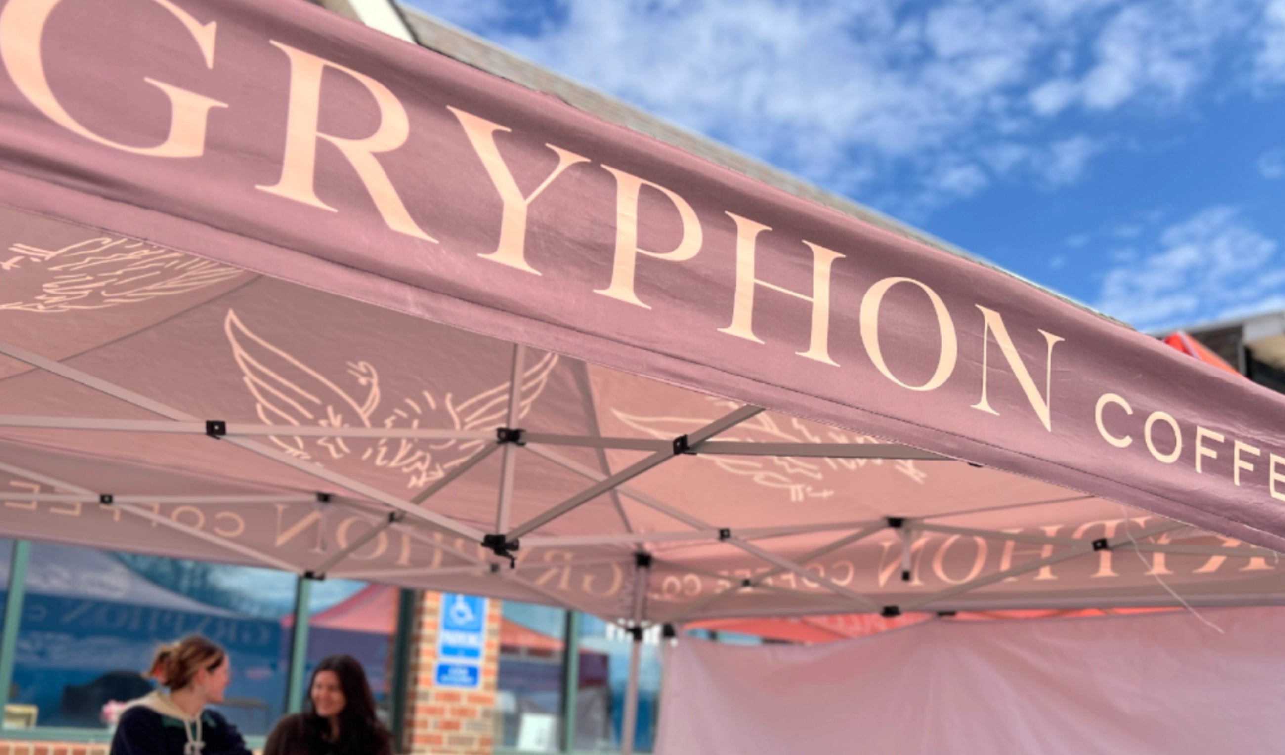 Gryphon Coffee tent with baristas smiling in the background