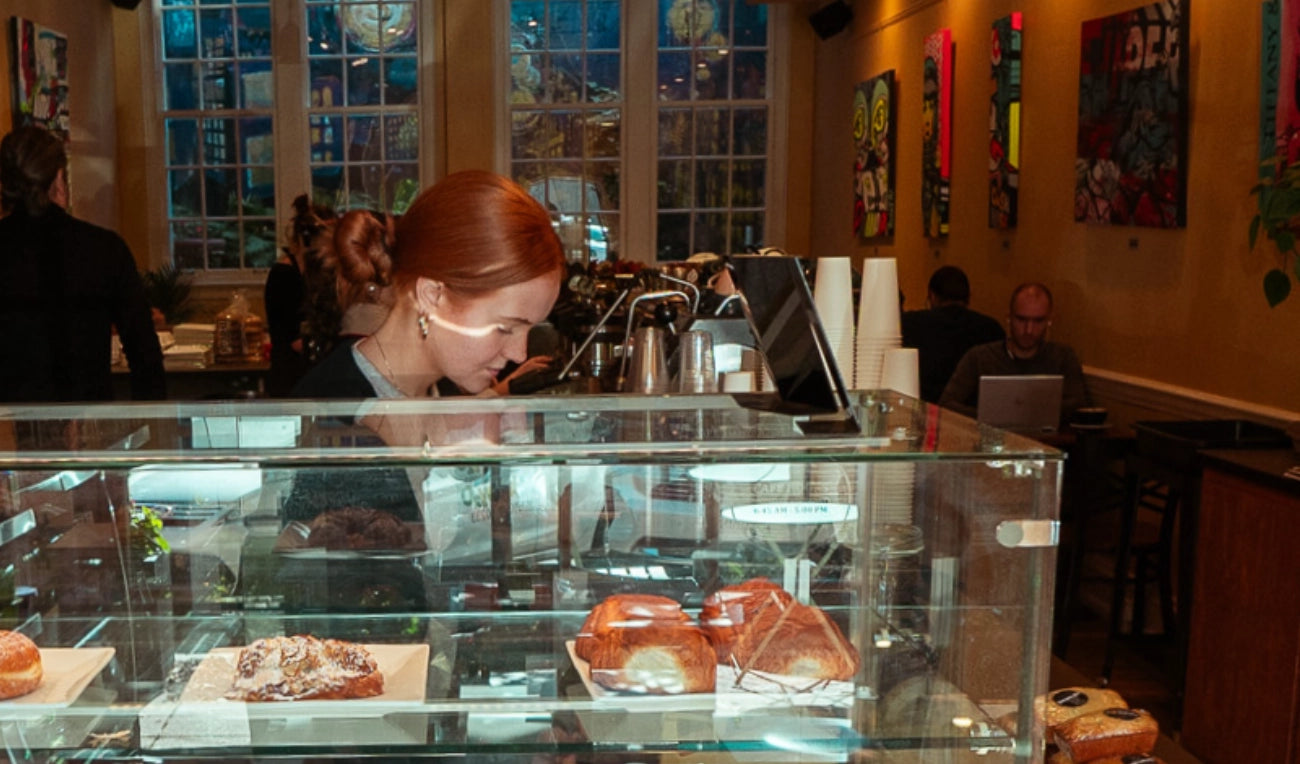 A pretty barista working behind a counter with pastries in cozy cafe in Wayne, PA.
